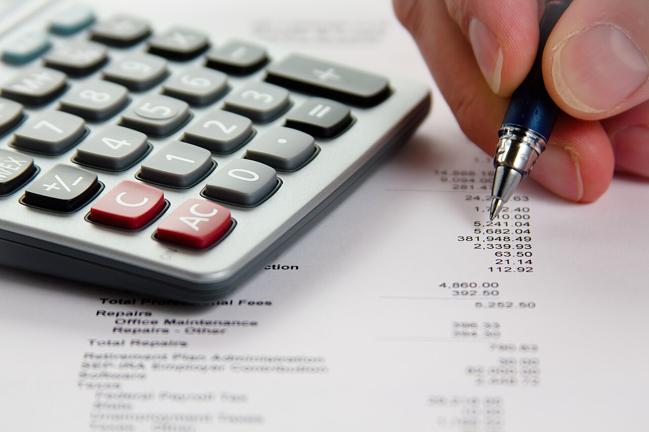 Pessoa analisando dados financeiros com calculadora e relatórios impressos